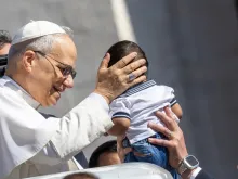 Papa Leão XIV abençoando uma criança depois da segunda audiência-geral de seu pontificado, em 28 de maio