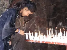 Jovem acende vela em santuário mariano no Paquistão.