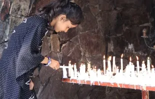 Jovem acende vela em santuário mariano no Paquistão.