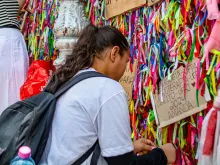 Devota amarra fitinha no portão da basílica santuário de Nazaré, em Belém (PA)