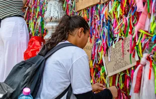 Devota amarra fitinha no portão da basílica santuário de Nazaré, em Belém (PA)