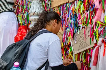 Devota amarra fitinha no portão da basílica santuário de Nazaré, em Belém (PA)