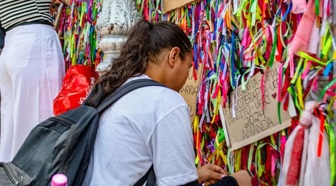 Devota amarra fitinha no portão da basílica santuário de Nazaré, em Belém (PA)