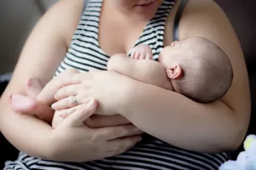 Uma mãe embala seu filho recém-nascido.