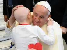 Papa Francisco abraça uma criança na Sala Paulo VI do Vaticano.