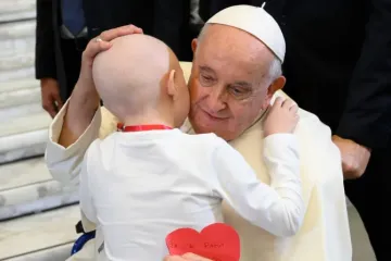 Papa Francisco abraça uma criança na Sala Paulo VI do Vaticano.