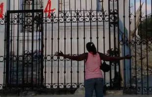 Uma mulher haitiana ajoelhada em oração em frente à Catedral de Porto Príncipe, capital do país.