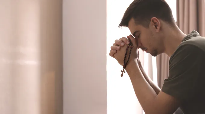 Imagem ilustrativa homem rezando o terço
