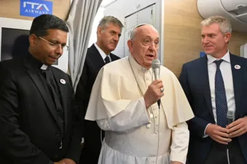 Papa Francisco fala a jornalistas a bordo do avião papal com o futuro cardeal George Jacob Koovakad