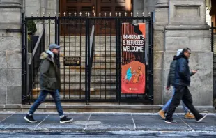 Pessoas passam por igreja com faixa dizendo "Imigrantes e Refugiados Bem-Vindos" em Nova York, EUA, em 24 de janeiro de 2025.