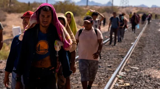 Grupo de migrantes caminha ao longo de trilhos de ferrovia para chegar à fronteira entre o México e os EUA ?? 