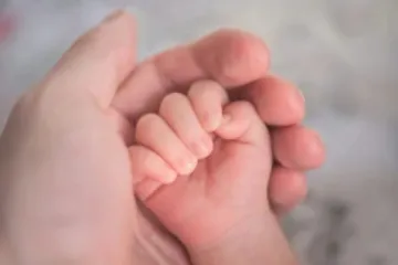 Mão segurando mão de bebê