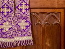 Estola roxa e confessionário.