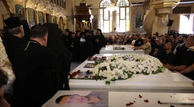 Enlutados se reúnem ao redor dos caixões brancos de alguns dos fiéis que morreram num ataque terrorista na igreja ortodoxa grega de Santo Elias ?? 