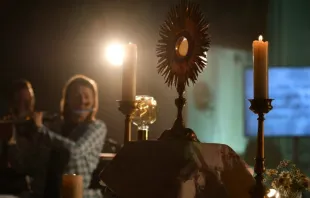 Ostensório com o Santíssimo Sacramento é exibido no altar em adoração eucarística em evento de Pentecostes da Comunidade de Loreto, com música ao vivo.