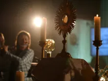 Ostensório com o Santíssimo Sacramento é exibido no altar em adoração eucarística em evento de Pentecostes da Comunidade de Loreto, com música ao vivo.