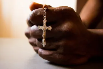 Mãos seguram terço