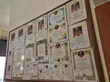 Placas penduradas no escritório da caridade papal na Cidade do Vaticano mostram diferentes modelos de certificados de bênção papal que podem ser encomendados.