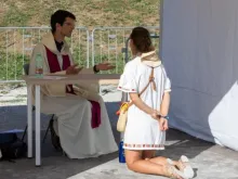 Penitente se ajoelha diante de padre em evento de confissão hoje (1) no Circo Máximo, em Roma.