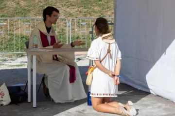 Penitente se ajoelha diante de padre em evento de confissão no Circo Máximo, em Roma, em 1° de agosto de 2025