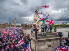 Manifestantes agitam bandeiras da Union Jack e da Cruz de São Jorge no protesto Unite the Kingdom na ponte de Westminster, perto do parlamento britâncio, em  Londres, em 13 de setembro de 2025.