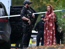 Policial armado conversa ontem (2) com membro da comunidade local do lado de fora da sinagoga da Congregação Hebraica de Heaton Park, em Crumpsall, norte de Manchester, Inglaterra.