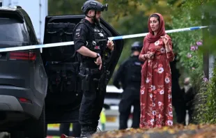 Policial armado conversa ontem (2) com membro da comunidade local do lado de fora da sinagoga da Congregação Hebraica de Heaton Park, em Crumpsall, norte de Manchester, Inglaterra.
