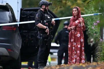 Policial armado conversa com membro da comunidade local do lado de fora da sinagoga da Congregação Hebraica de Heaton Park, em Crumpsall, norte de Manchester, Inglaterra em 2 de outubro de 2025