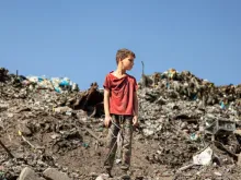 Criança em pé sobre escombros na Faixa de Gaza.