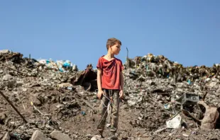 Criança em pé sobre escombros na Faixa de Gaza.