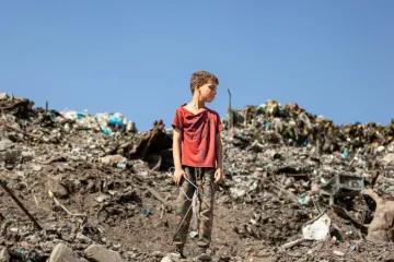 Criança em pé sobre escombros na Faixa de Gaza