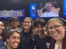 Os adolescentes Mia Smothers, Ezequiel Ponce, Micah Alcisto, Elise Wing e Chris Pantelakis, e a moderadora Katie McGrady (à direita), tiram uma selfie com o papa Leão XIV num encontro digital ao vivo no Lucas Oil Stadium, em Indianápolis, EUA, em 21 de novembro de 2025.