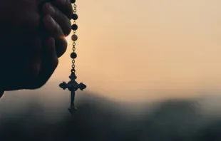 Mãos segurando terço.