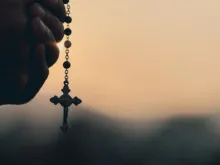 Mãos segurando terço.