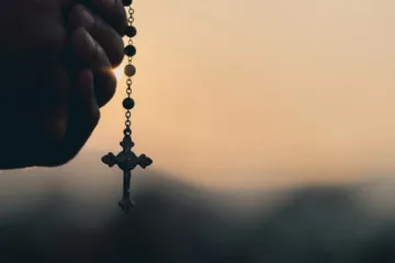 Mãos segurando terço