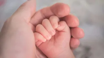 Mão segurando mãos de bebê. Imagem meramente ilustrativa.