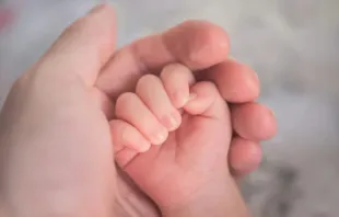 Mão segurando mãos de bebê. Imagem meramente ilustrativa.