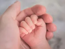 Mão segurando mãos de bebê. Imagem meramente ilustrativa.