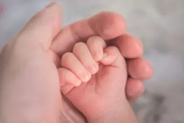 Mão segurando mãos de bebê