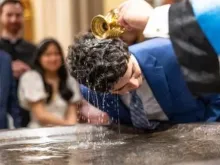 Estudante é batizado na missa da vigília pascal na basílica do Sagrado Coração, em Notre Dame, EUA, em 19 de abril de 2025.