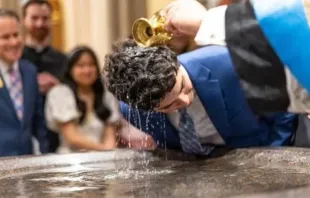 Estudante é batizado na missa da vigília pascal na basílica do Sagrado Coração, em Notre Dame, EUA, em 19 de abril de 2025.