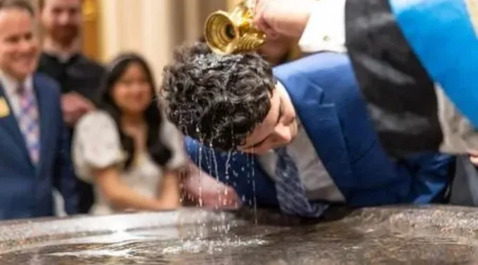 Estudante é batizado na missa da vigília pascal na basílica do Sagrado Coração, em Notre Dame, EUA, em 19 de abril de 2025 ?? 