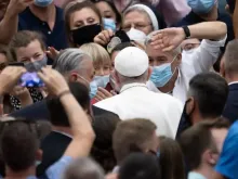 Pessoas usando máscaras cumprimentam o Papa Francisco