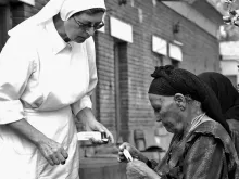 Uma religiosa entrega remédio a uma leprosa.