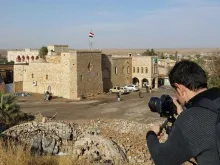 Jovem fotografando uma casa danificada em Qaraqosh (Iraque) 