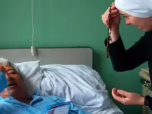 Religiosa rezando com um doente 