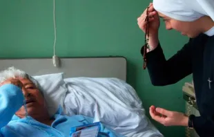 Religiosa rezando com um doente