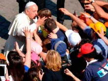 Papa Francisco cumprimenta uma criança na Praça de São Pedro.