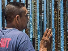 Um homem olha para o outro lado do muro fronteiriço entre o México e os Estados Unidos.