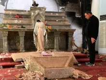 Sacerdote olhando para uma imagem da Virgem Maria decapitada, entre os escombros de uma igreja destruída pelo Estado Islâmico no Iraque.